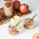 dwie szklanki z wodą z octem jabłkowym, udekorowane jabłkami, korą cynamonu i rozmarynem