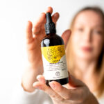 kobieta trzyma w dłoni buteleczkę ekstraktu propolisowego