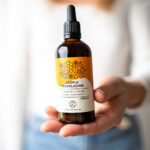 kobieta trzyma w dłoni buteleczkę ekstraktu propolisowego